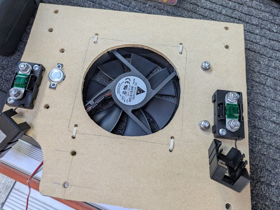 The board that the converter mounts to with the fan behind. The metallic round thing on the left is the 50°C thermal switch. It touches the surface of the heat sink and I smeared a bit of thermal paste on it before mounting.