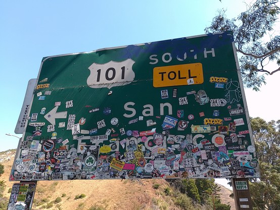 A road sign to San Francisco covered in stickers.